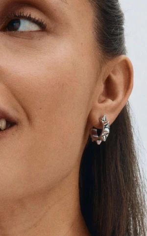 Silvriga örhängen med nitar från edblad - Coola silvriga örhängen i ringmodell med tydliga nitar runt hela ringen. De har en edgy vibe och är perfekta för att ge din look lite extra attityd. Passar dig som gillar att sticka ut och vill ha något unikt i smyckeslådan.