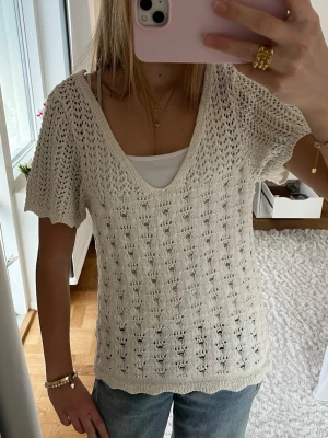 Stickad vit topp från ONLY - Säljer en ljus stickad topp från ONLY i storlek M. Toppen har korta ärmar, v-ringad hals och ett luftigt, virkat mönster. Perfekt till jeans eller kjol.