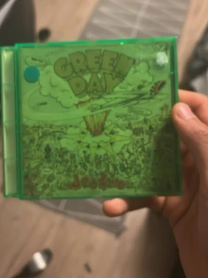 Green day cd - Bilderna visar ett Green Day-album (Dookie) i ett grönt CD-fodral, men ingen väst finns med på bilderna.