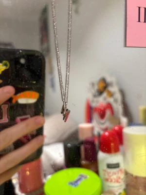 Silverfärgad blixt-halsband ifrån Edblad - Snyggt halsband med en blixtformad berlock i silverfärgad metall. Kedjan är tunn och stilren, perfekt för att ge din outfit lite edge. Blixten är liten och minimalistisk, vilket gör halsbandet lätt att matcha med andra smycken. Ask medkommer