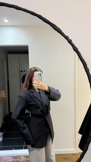 Svart kavaj med klassisk passform - Snygg svart kavaj med klassisk krage och enkel knäppning framtill. Modellen har lång ärm och en rak, något loose siluett som ger en cool vibe. Perfekt att styla med jeans eller dressade byxor. Materialet känns slätt och har en stilren look.