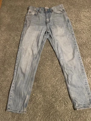 Ljusblå jeans från 157, W28 L32 - Säljer ett par ljusblå jeans från 157 i klassisk femficksmodell. Jeansen har raka ben och normal passform, med snygga kontrastsömmar och en enkel design. Perfekt för dig som gillar en clean och avslappnad stil.