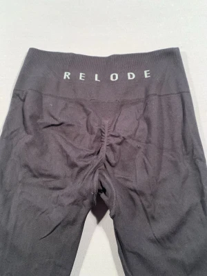 Svarta leggings från Relode - Säljer ett par svarta leggings från Relode med hög midja och stretchigt material. Perfekta för träning eller chill dagar. Tight passform som framhäver benen och bred resår i midjan för extra komfort.