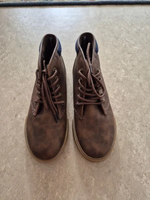 Kängor - Snygga bruna kängor från Nautica i storlek 36. Skorna har snörning, rund tå och platt gummisula. Bruna kängor i skinnimitation (mockastil).. Använda mycket lite, i fint skick. Perfekt för dig som gillar en enkel och stilren look.