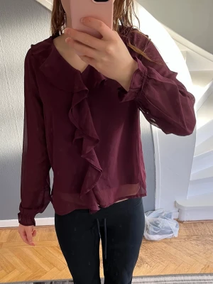 Vinröd blus - Vinröd blus från Ullared märket samsa. Denna blus är perfekt till jul. Den har voland framme och vid armarna. Storlek 146-152.