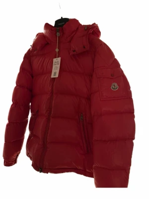 Moncler Maya Jacka Röd - Moncler Maya – Röd, Storlek 5  Mycket snygg Moncler Maya-jacka i klassisk röd färg, storlek 5. Skick cirka 8/10 med lite slitage på en knapp och två små fläckar. Köpt på Vestiaire Collective och verifierad via deras autentiseringstjänst. Säljes eftersom den tyvärr inte passar mig. Perfekt för dig som vill ha en varm och stilren lyxjacka.