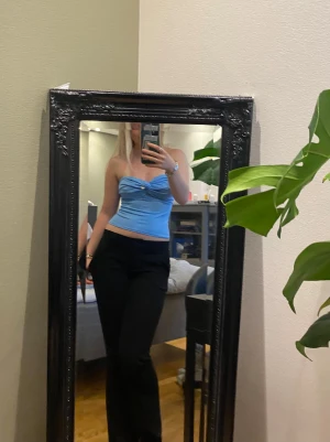 Blå bandeau tubtopp  - Säljer en ljusblå bandeau tubtopp med en söt hjärtformad detalj framtill. Toppen är croppad och har en tight passform som framhäver midjan. Materialet känns mjukt och stretchigt, perfekt för dig som gillar att sticka ut med färg. Supersnygg till svarta byxor eller kjol!