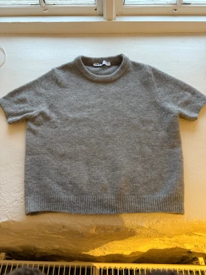 Grå stickad kortärmad tröja från ZARA - Supermjuk grå stickad tröja från ZARA med korta ärmar och rund hals. Knappt använd så i väldigt fint skick 
