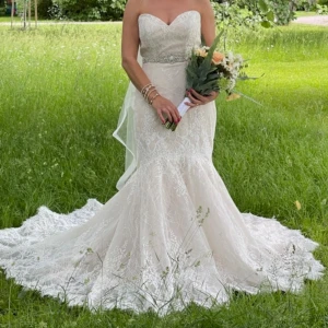 Romantisk spetsklänning med släp - Drömmig långklänning i champagnefärgad spets med vacker släp och figurnära passform. Axelbandslös design med markerad midja och fina spetsdetaljer över hela klänningen. Perfekt för dig som vill ha en elegant och klassisk look. Har använd bara för bröllopsfest. Den är helt ny och medföljer allt som  i paket.