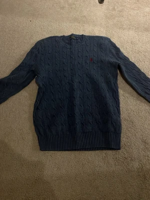Blå kabelstickad tröja Polo Ralph Lauren - Säljer en marinblå kabelstickad tröja från Polo Ralph Lauren i storlek S. Tröjan har rund hals. Hör av dig om du har frågor