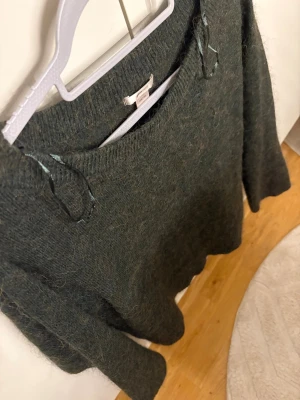 Mörkgrön stickad tröja Gina Tricot - Mysig mörkgrön stickad tröja från Gina Tricot i storlek 158/164. Tröjan har rund hals och långa ärmar, perfekt för att hålla sig varm under kyliga dagar. Den har en fluffig och mjuk känsla som gör den extra skön att bära.