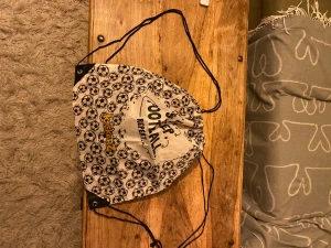 Vit och svart gympåse från Kickerz - Säljer en vit och svart gympåse från Kickerz med coolt fotbollsmönster över hela väskan. På framsidan står det 'Eat. Sleep. Football. Repeat.' i svart text. Väskan har snörning och svarta hörnförstärkningar. Perfekt för fotbollsträningen!