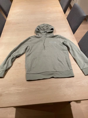 Ljusgrön hoodie Peak Performance S - Snygg ljusgrön hoodie från Peak Performance i storlek S. Tröjan har huva med snörning, ribbade muddar och en klassisk magficka. Materialet är mjuk bomull och polyester, perfekt för chill dagar. Diskret logga på bröstet ger en clean look. Inga skador på tröjan men haft den rätt länge.