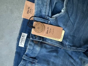Slim fit blå jeans från Lindex - Snygga blå jeans från Lindex i slim fit-modell med tighta ben och klassisk femficksdesign. Jeansen har en justerbar midja och dragkedja i gylfen. Materialet är mjukt denim och färgen är mellanblå med lätt slitning för en cool look.