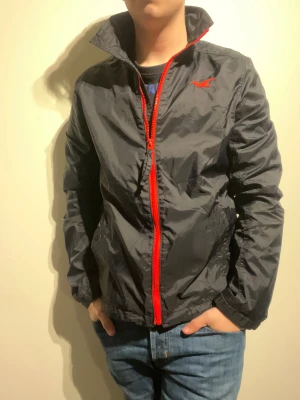 Hollister Vindjacka  - Hej! Säljer nu denna väldigt snygga Hollister vindjacka.  Storlek M Medium   Färg: Svart och Röd Skick: Mycket gott – endast använd vid enstaka tillfällen  Skickas spårbart eller hämtas upp efter överenskommelse. Vid intresse – hör gärna av dig.  Skriv vid frågor eller ifall du vill ha fler bilder:)   