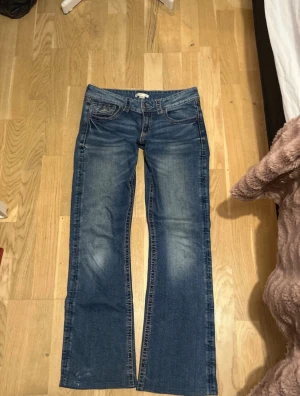 Blå bootcut jeans från Gina Tricot - Snygga blå jeans från Gina Tricot i storlek 164. Modellen har klassisk bootcut. Fickor både fram och bak, bakfickorna har lock och knapp. Perfekt för dig som gillar retrovibbar och bekväm passform.
