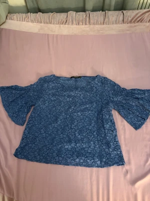 Blå spetsblus från Reserved - Säljer en blå blus från Reserved i storlek 38. Blusen är helgjord i spets med blommigt mönster och har vida, korta ärmar som ger en cool och luftig vibe. Perfekt för dig som gillar detaljer och vill sticka ut med en snygg topp.💙