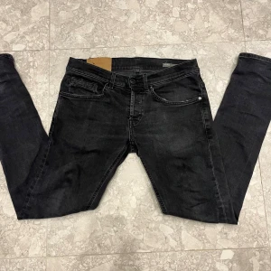 dondup george - Snygga svarta jeans från Dondup i storlek 29. Modellen har klassisk femficksdesign, smal passform och svarta sömmar. Jeansen är tillverkade i stretchigt denim och har en diskret logga på bakfickan. Perfekt för dig som gillar stilrena och moderna jeans.