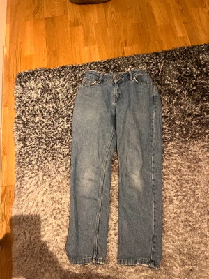 Blå raka jeans från Grunt - Snygga blå jeans från Grunt med klassisk femficksdesign och raka ben. Jeansen har gul kontrastsöm, knapp och dragkedja framtill samt läderpatch med logga bak i midjan. Perfekt för dig som gillar en enkel och tidlös look.
