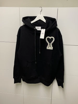 Ami Paris Hoodie - Säljer en helt ny Hoodie , aldrig använd. Storlek M. Snabb frakt fraktas inom 24h efter köp. Kan härmas i Haninge, skriv gärna vid fler frågor.