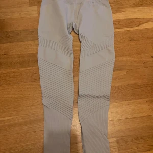 Ljusgrå ribbade leggings från Aim'n - Säljer ett par ljusgrå leggings från Aim'n i storlek S. De har ribbade detaljer och snygga diagonala mönster längs benen, samt små hål för extra ventilation. Materialet är stretchigt med 92% polyamid och 8% elastan.