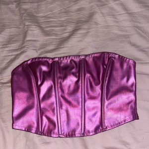 Rosa fest topp - Säljer en metallic rosa korsett från Gina Tricot i storlek XS. Toppen är axelbandslös och har en snygg glansig finish med markerade sömmar framtill. Baksidan har en dragkedja för enkel på- och avtagning. Perfekt för alla nattens fester! Den har tappat lite trådar o färg men verkligen inget man ser eller tänker på!!💕💕