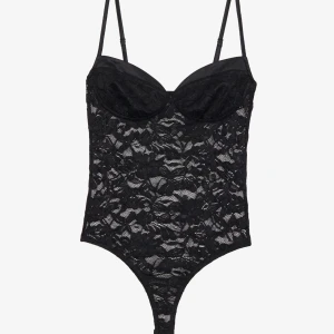 Svart spets body  med axelband - Säljer en svart korsett med tunna justerbara axelband och vacker spets över hela plagget. Kuporna är formade för extra stöd och den har en tight passform som framhäver siluetten. Endast använd en gång!