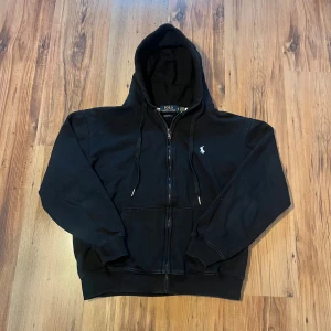 Svart hoodie från Polo Ralph Lauren - Svart zip hoodie från Polo Ralph Lauren 🐎           Size M, men sitter mer åt XS hållet i storlek         Längd (55cm), bredd (50cm), ärm (50cm)           I mycket bra skick utan defekter 👍                     Hör av er om ni har frågor 🤩