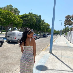 Pastellfärgad stickad långklänning - Supersöt långklänning i stickat material med pastelliga ränder i vitt, rosa, grön och lila. Klänningen har smala axelband, rak halsringning och en liten slits nertill. Perfekt för sommarens varma dagar och ger en chill vibe.