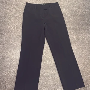 Svarta kostymbyxor från Bik Bok - Stilrena svarta kostymbyxor från Bik Bok med raka ben och klassisk midja. Byxorna har bälteshällor och sidofickor, vilket ger en clean och snygg look. Perfekta för dig som gillar minimalistisk stil och vill ha ett par byxor som funkar till många outfits.