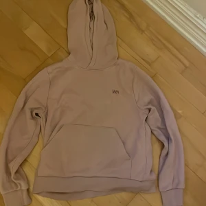 Ljusrosa hoodie från WA - Ljusrosa hoodie från WA med stor magficka och huva. Tröjan har ett stilrent WA-tryck på bröstet och är tillverkad i mjuk bomullsmix. Perfekt för chill dagar och har ribbade muddar vid ärmslut och nederkant. Snygg och enkel att matcha med jeans eller mjukis.