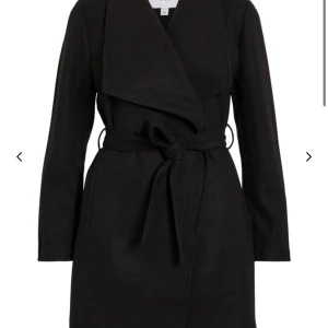 Svart omlott kappa med bälte !Oanvänd! - Stilren svart kappa från Vero Moda med omlott-design och brett bälte i midjan. Jackan har långa ärmar och en snygg krage som ger en cool siluett. Perfekt för dig som gillar minimalistisk och trendig look. 