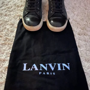 Lanvins med dustbag - Snygga mörkgröna sneakers från Lanvin Paris med rund tå och platt vit sula. Ovandelen är i mocka med detaljer i blankt skinn på tån och snörning framtill. Klassisk och stilren design med metallöglor och logga under sulan. Perfekt för dig som gillar exklusiva märken.