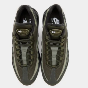 Nike Air Max 95 mörkgröna sneakers - Nike Air Max 95 sneakers i mörkgrönt med svarta detaljer och synlig Air-sula. Ovandel i mesh och syntet med snörning och rund tå. Snygga vågiga paneler på sidorna och diskret Swoosh-logga i silver på hälen. Perfekt för dig som gillar streetwear och sportig stil.HELT NY OÖPPNAD MED KARTONGEN. 
