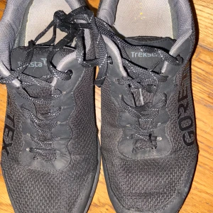 Svarta Treksta Olympus Low GTX sneakers - Svarta Treksta Olympus Low GTX sneakers med snörning och mesh-överdel. Skorna har Gore-Tex-material som gör dem vattentäta och andningsbara. Snygg, sportig design med låg profil och rund tå. Perfekta för dig som gillar outdoor och vill ha bekväma skor med bra grepp.