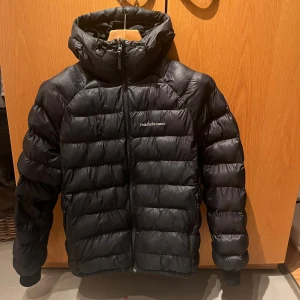 Svart Peak Performance dunjacka M - Säljer en välvårdad Peak Performance dunjacka i svart färg, storlek M. Jackan är varm, lätt och bekväm – perfekt för vintern och kyliga höstdagar.  En ficka har en liten reva, men det syns inte och påverkar inte användningen. Alla dragkedjor fungerar som de ska. I övrigt är jackan i mycket gott skick – inga fläckar eller slitage.  Förvarad noggrant och tvättad enligt instruktionerna.