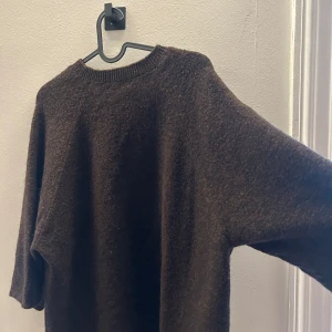 Mörkbrun stickad tröja med rund hals - Mysig mörkbrun stickad tröja med rundad halsringning och lite lösare passform. Tröjan har långa ärmar och är perfekt för kyligare dagar. Enkel och stilren design som funkar till det mesta.