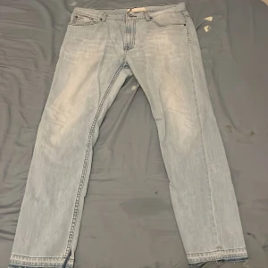 Ljusblå jeans från Dressmann, 36/30 - Säljer ett par ljusblå jeans från Dressmann med klassisk femficksdesign och raka ben. Jeansen har tydliga kontrastsömmar och är tillverkade i bomullsmaterial. Passar dig som gillar en enkel och clean look med lite retrovibe.