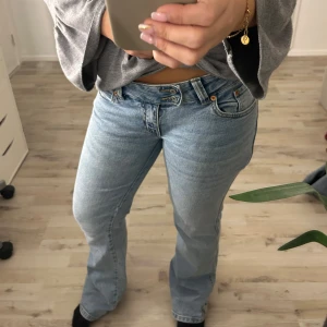 Ljusblå bootcut jeans med broderad ficka - Snygga ljusblå jeans med bootcut passform och broderad detalj på bakfickan. Jeansen har klassisk femficksdesign, låg midja och slitna benslut,se bild. Perfekta till sneakers eller boots.storlek S och length short