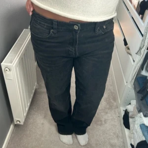 Svarta raka jeans med midja - Säljer ett par svarta jeans med rak passform. Jeansen har normal midja och är tillverkade i ett mjukt denimtyg. 