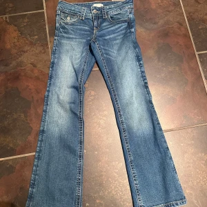 Blå bootcut jeans från Gina Tricot - Snygga blå jeans från Gina Tricot med bootcut-ben och klassiska fickor med lock och knapp både fram och bak. Jeansen har kontrastsömmar och normal passform. Perfekta för dig som gillar en tidlös denimlook. Använda 2 ggr innan de blev urvuxna. 