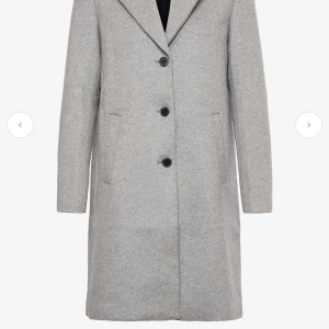 Ljusgrå ullkappa från Selected Femme - Stilren ljusgrå kappa från Selected Femme i ullmix med klassisk krage, tre knappar framtill och raka fickor. Kappan har slät yta, knappar vid ärmslut och helfodrad insida. Perfekt för dig som vill ha en clean och tidlös look. Endast använd några få gånger. Nypris: 2799