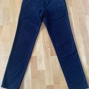 Oscar Jacobson byxor - Snygga mörkblå manchesterbyxor med klassisk rak passform och diskreta fickor både fram och bak. Byxorna har bälteshällor och är tillverkade i mjuk manchester som ger en stilren och chill vibe. Perfekta för dig som gillar en tidlös look. Byxorna är mörkare i verkligheten än på bilden.