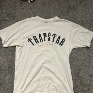 Trapstar t-shirt - Vit t-shirt från Trapstar i bra skick. Bara ytterst lite urtvättad på den röda texten. Köpt på trapstars hemsida
