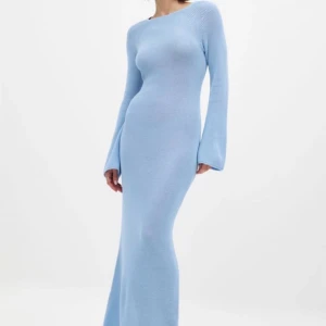 Ljusblå stickad långklänning med snörning - Supersnygg ljusblå stickad långklänning med lång ärm och öppen rygg med snörningsdetalj. Klänningen har en tight passform och vida ärmar, perfekt för dig som vill sticka ut med en cool och trendig look.