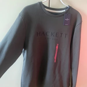 Mörkgrå sweatshirt från Hackett London - Riktigt snygg mörkgrå sweatshirt från Hackett London. Tröjan är i storlek M och har aldrig använts nypris: 1699kr, Kvitto finns
