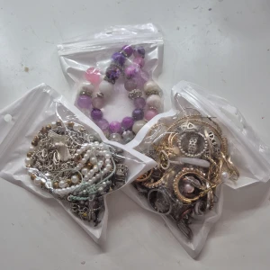 Mixade smycken i tre påsar - MISTERY! Tre påsar fyllda med olika smycken: armband, halsband, kedjor i silver och guld samt flera ringar och örhängen i olika former och färger. Perfekt för dig som gillar att variera din stil och mixa accessoarer.