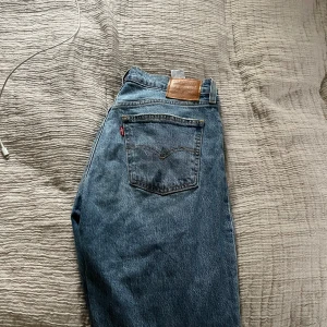 Levi's 501 blå jeans straight fit - Klassiska blå Levi's 501 jeans med rak passform och låg/mellan midjehöjd. Jeansen har fem fickor, ikonisk läderpatch bak och röd Levi's-tagg på bakfickan. Tillverkade i slitstarkt bomullsdenim. Andvända 1-2 gånger