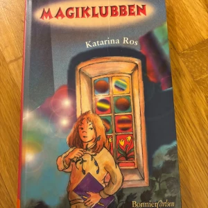 Magiklubben - En färgstark bok med magiska vibbar! Omslaget visar en ung person med en bok i handen framför ett mystiskt fönster med färgglada mönster. Perfekt för dig som gillar spänning och magi i vardagen.