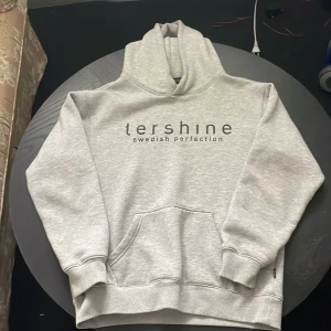 Grå hoodie från Tershine - Snygg ljusgrå hoodie från Tershine med tryck på bröstet. Klassisk ficka framtill, mjuk insida och huva. Perfekt för chill dagar eller när du vill ha en enkel och stilren look.